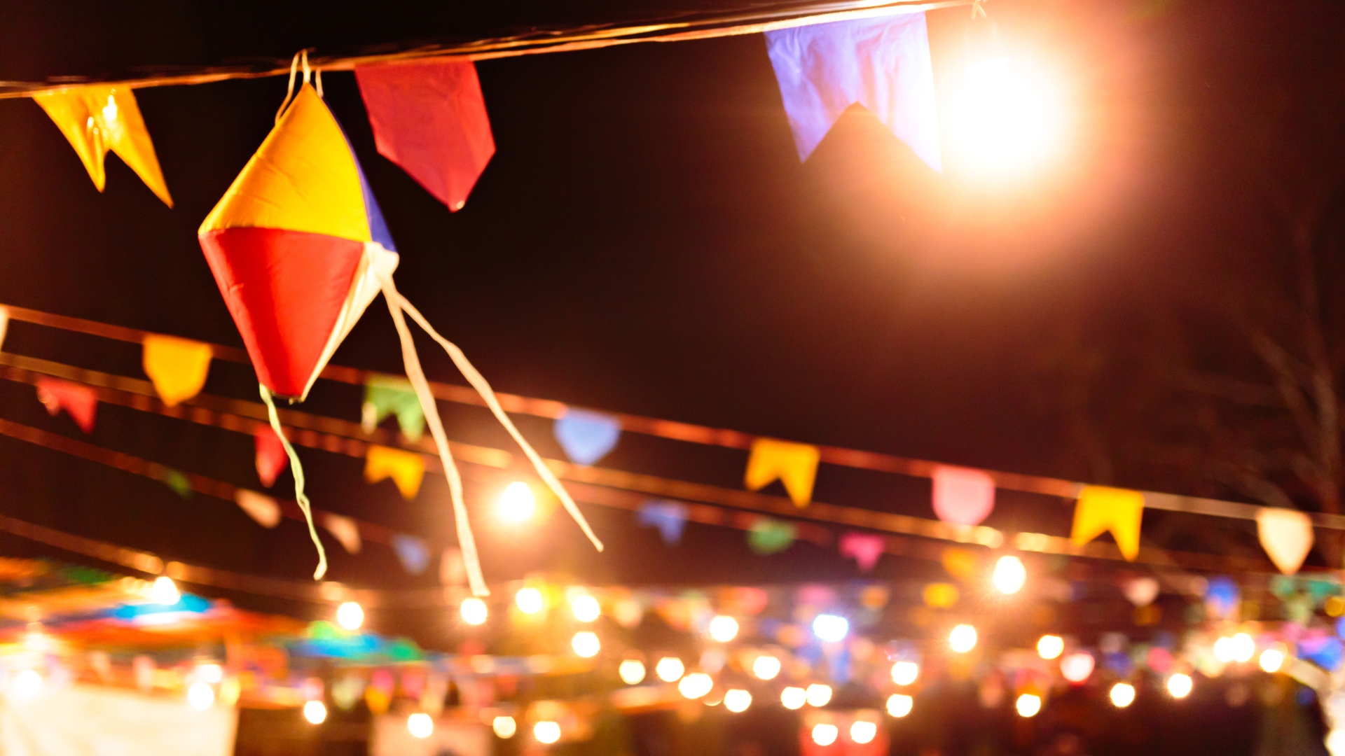 Imagem de um céu noturno com bandeirinhas e balões de festa junina