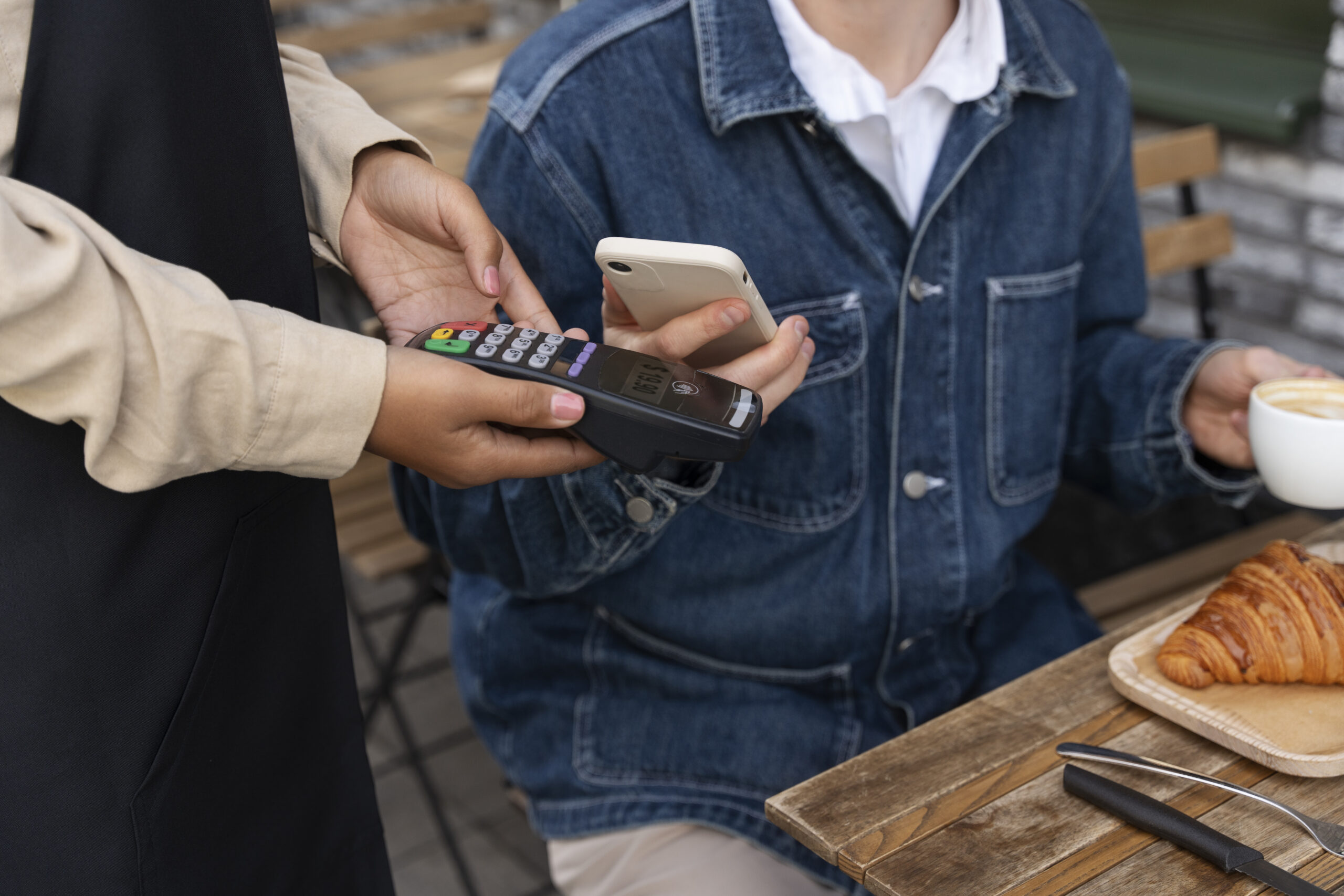 Pessoa pagando a conta em um restaurante aproximando o celular da máquina de cartão