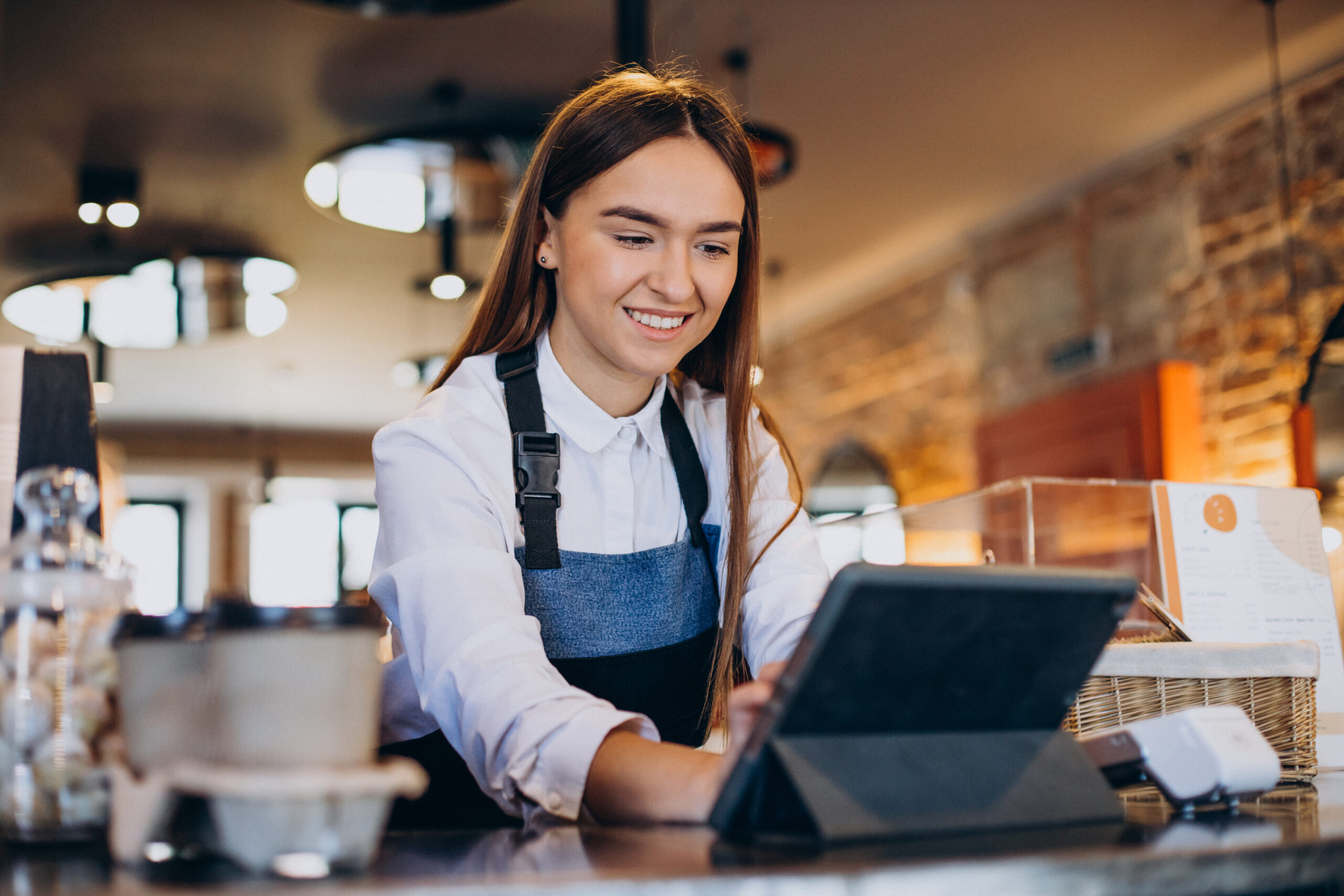 Funcionária de um restaurante mexendo no sistema de gestão do estabelecimento por um tablet