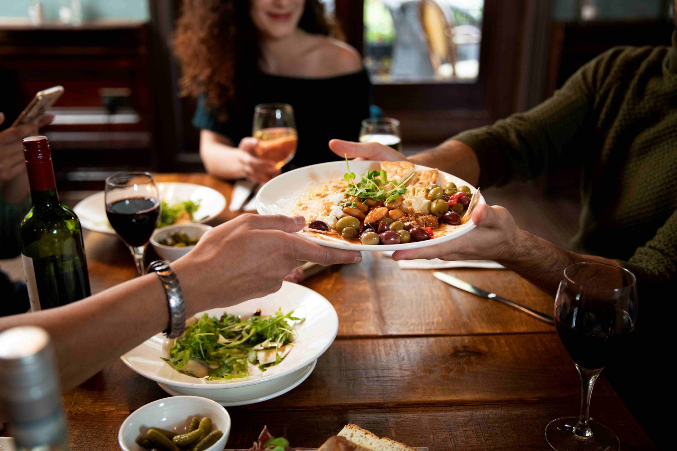 Mesa de restaurante com pessoas segurando um prato