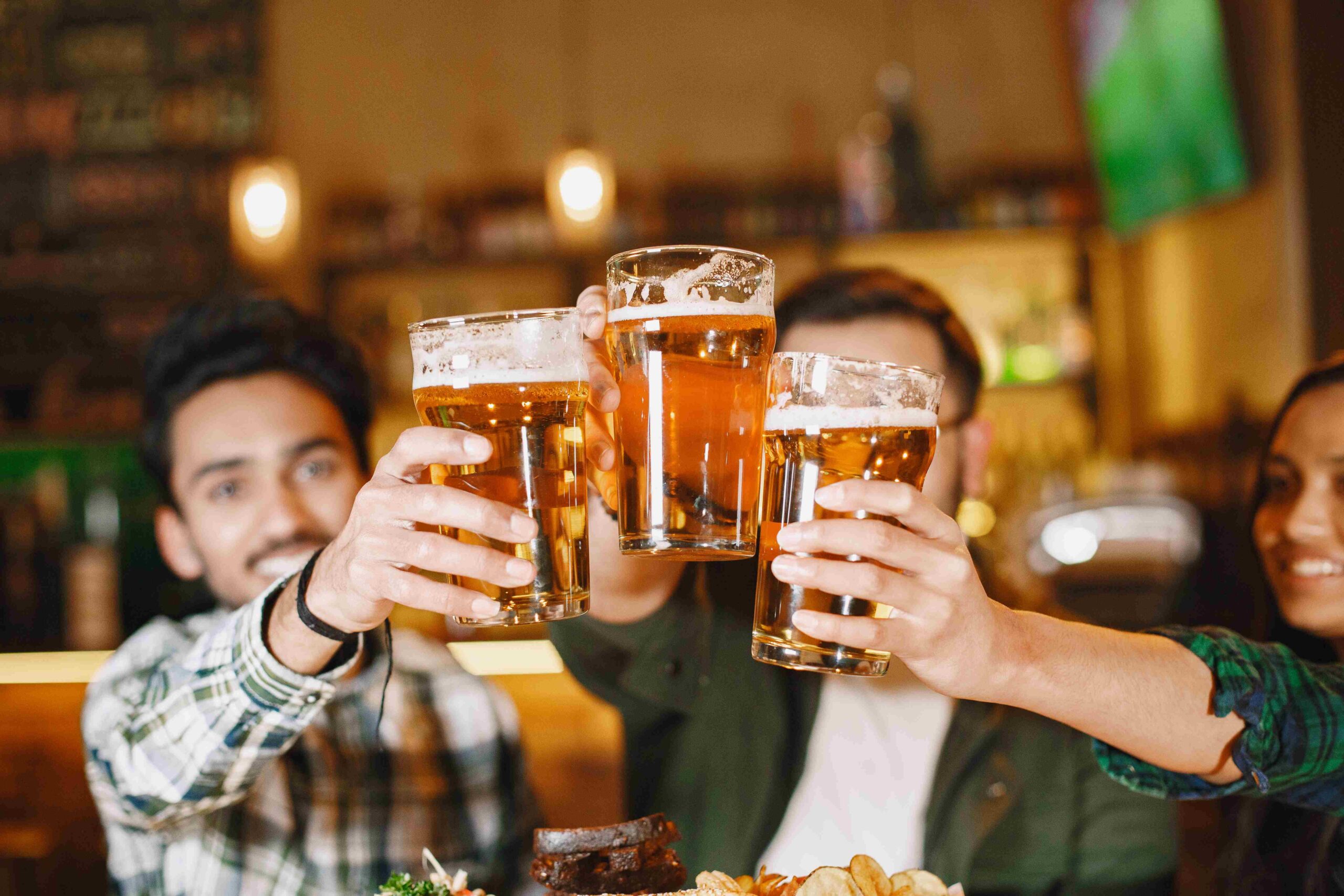 Homens brindando com copos de cerveja em um pub